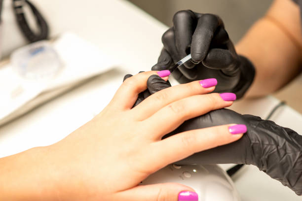 プロのマニキュア。ネイリストは、美容院でクライアントの女性の爪を紫色のマニキュアで接写しています。美容業界のコンセプト。 - beautiful glamour motion purple ストックフォトと画像