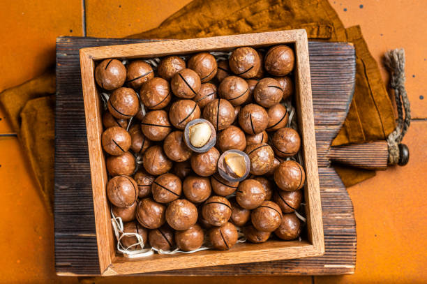 istock Macadamia natural nuts in a box. Orange background. Top view 1470932658