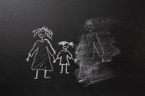 Chalk drawing of a child and parents on a blackboard, divorce trauma concept