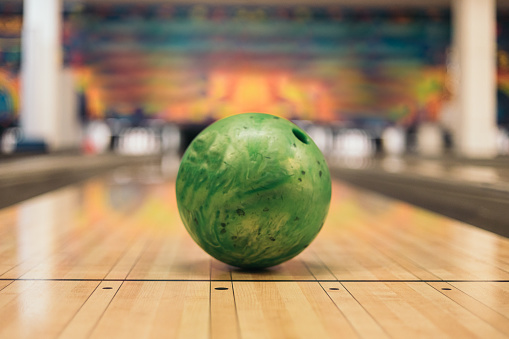 Green bowling ball on the track, active leisure game concept
