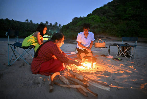 istock Three generation family sitting around a campfire and having a Barbeque on the beach 1470934211