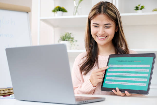 Young asian woman, english teacher holding digital tablet while teaching english language online class Young asian woman, english teacher holding digital tablet while teaching english language online class english spoken stock pictures, royalty-free photos & images