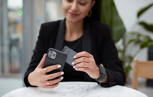 Business woman making contactless payment easily with a smart credit card held in front of the phone.