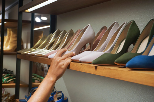 Unrecognizable Caucasian woman choosing leather shoes in a shoe store.