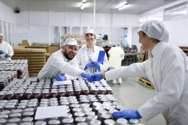 Smiling Workers In Pepper Processing Plant Shaking Hands And Getting Ready To Take Jars To Storage Room stock photo