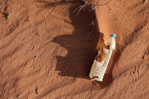 Plastic bottle in the sand (pollution concept).