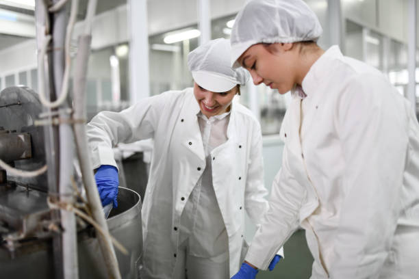 istock Smiling Female Workers Operating Machinery For Cottage Cheese Mixture In Food Processing Plant 1470940198