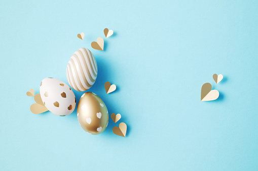 Gold painted Easter eggs on blue background. Horizontal composition with copy space. Easter concept.