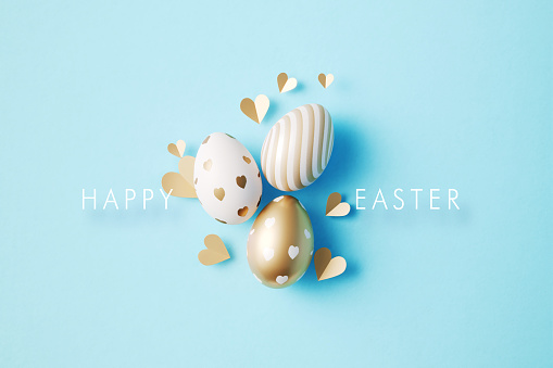 Gold painted Easter eggs and Happy Easter Day message on blue background. Horizontal composition with copy space. Easter concept.