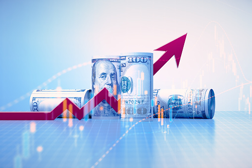 Rolled up 100 American Dollar bills, red arrow and stock market data over blue background. Horizontal composition with copy space. Finance concept.