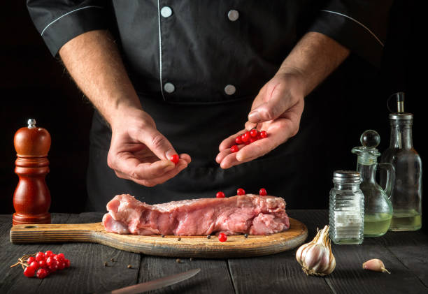 dans le restaurant, le chef de cuisine prépare de la viande de veau crue. avant la cuisson, le cuisinier met la viorne sur le bœuf. plat national - veal calf meat baking photos et images de collection