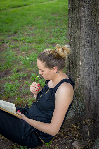 Young beautiful woman reading a book at the park