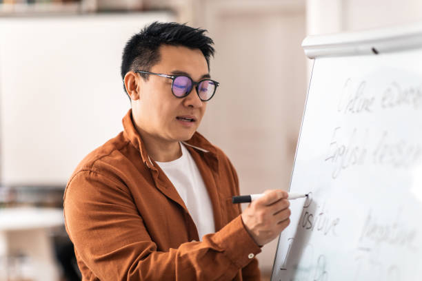 istock Korean Male Teacher Having Class Writing On Whiteboard In Classroom 1470958603