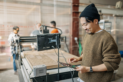 Portrait of the asian man working on the tablet in the foreground while students are in background