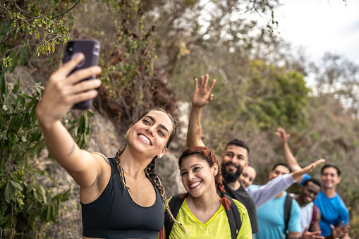 Mid adult woman taking a selfie with her friends during a hike outdoors