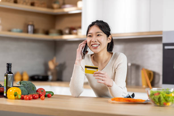 istock Cheerful asian lady making order, talking on smartphone 1470958972