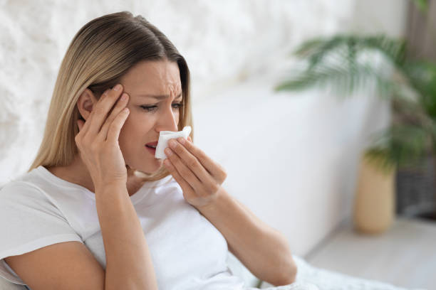 istock Ill blonde lady sneezing and touching her head 1470959219