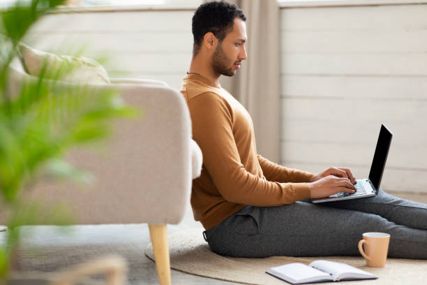 istock Arab man using laptop sitting on floor in living room 1470959284