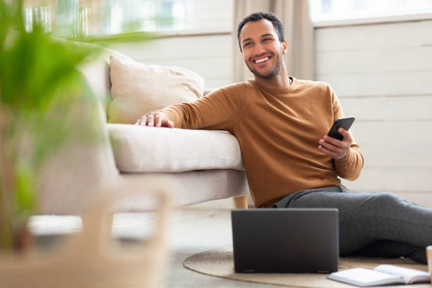 istock Young Arab man holding phone using pc at home 1470959304