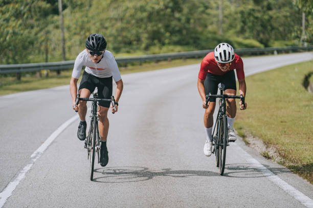 2人のアジア系中国人男性サイクリストがサイクリングイベントの農村シーンで競い合う - cycling shorts ストックフォトと画像