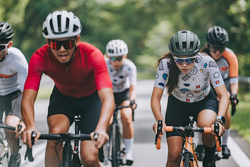 One athletic young man cycling outside. Sporty fit male wearing helmet and glasses while riding a bike on a road along the mountain for exercise. Endurance and cardio during a workout and training