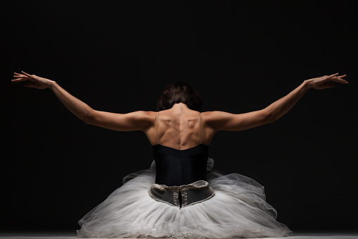 Half silhouette modern ballet dancer. Balerina posing on dark background