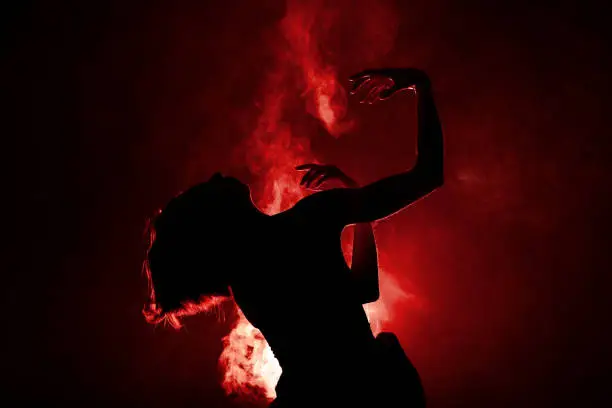 Silhouette modern ballet dancer. Ballerina posing against black with smoke in the background