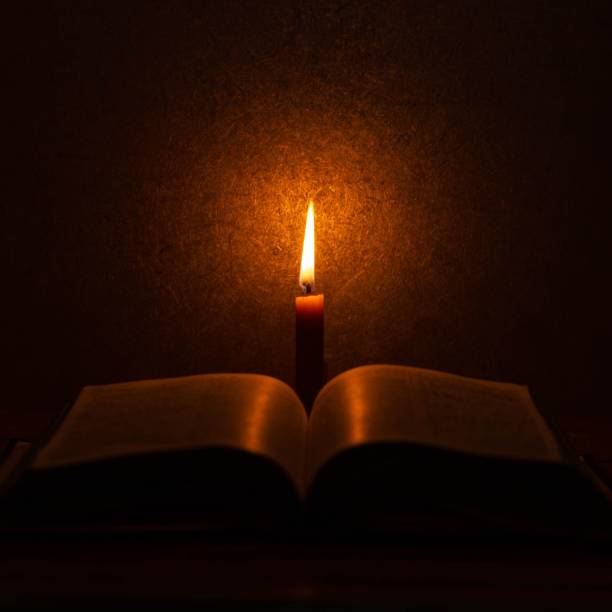 istock Book illuminated by a burning candle on a table 1470961556