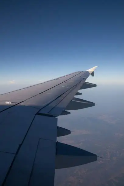 Aerial view of an airplane wing against a clear blue sky