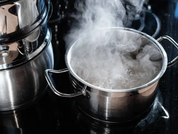 boiling water in saucepan on ceramic stove in home kitchen