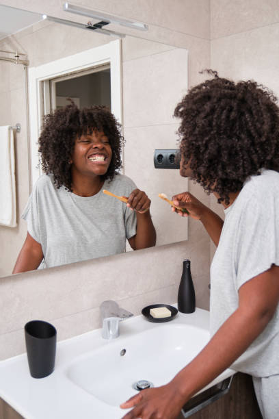 Young African woman maintaining her dental hygiene with a bamboo toothbrush. stock photo