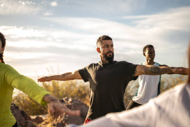 homem maduro durante uma aula de yoga ao ar livre - healthy lifestyle yoga vitality flexibility - fotografias e filmes do acervo