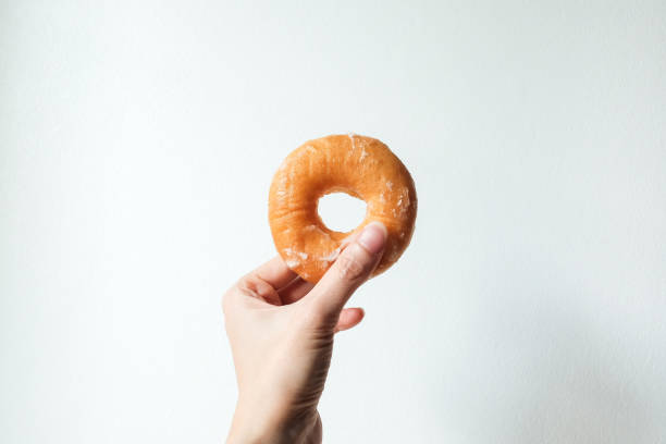 istock hand holding sweet delicious glazed donut on white background. 1470969782
