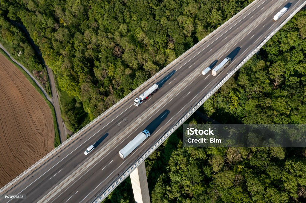 Truck traffic on highway bridge, aerial view Aerial view of truck traffic on highway bridge over a valley covered with forest. Truck Stock Photo