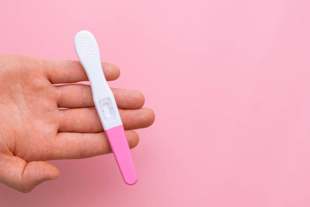 istock Man hand holding a pregnancy test on the pink background with copy space. 1470972257