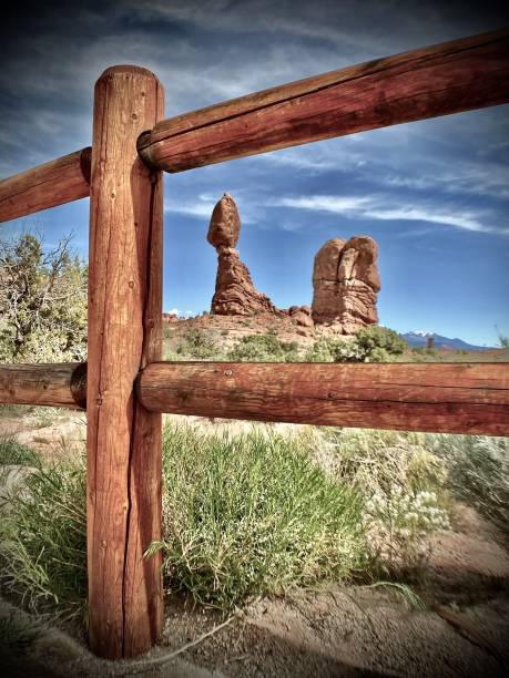 eingerahmt zwischen den zaunpfählen: ausgewogener fels besteht aus rotem entrada-sandstein. - usa arches national park balanced rock colorado plateau stock-fotos und bilder