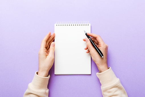 Woman hand with pencil writing on notebook. Woman working on office table. Female hand holding pencil and sketchbook. Mock-up Concept.