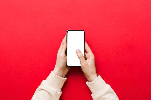 Top view of woman hands holding smart phone with blank copy space screen for your text message or information content. woman hand using phone white screen on top view. vista superior de las manos de la mujer sosteniendo un teléfono inteligente con una pantalla de espacio de copia en blanco para su mensaje de texto o contenido informativo. mano de mujer usando la pantalla blanca del teléfono en la vista superior
