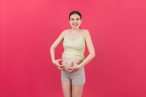 istock Pregnant woman scratching her belly on colored background 1470974231