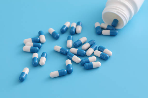 istock pills capsules with bottle isolated on blue background 1470975773
