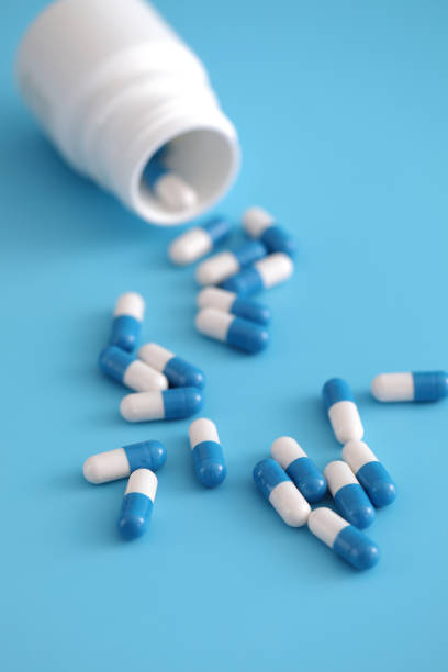 istock pills capsules with bottle isolated on blue background 1470976893