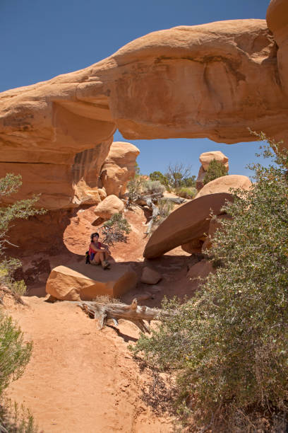 Woman sits under Mono Arch Grand Staircase Escalante National Monument Utah stock photo