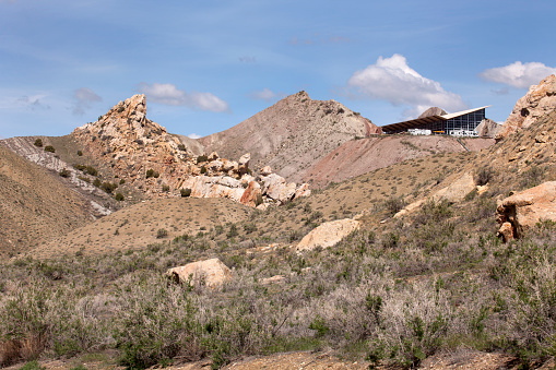 Following the appearance of the nearby geology, the Quarry Exhibit Hall with parked RVs angular design stands in the Dinosaur National Monument, Utah.