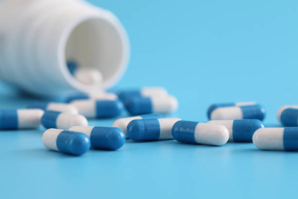 istock pills capsules with bottle isolated on blue background 1470978142
