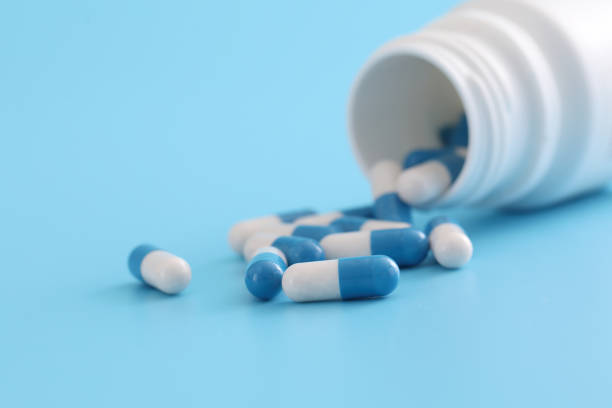 istock pills capsules with bottle isolated on blue background 1470979300