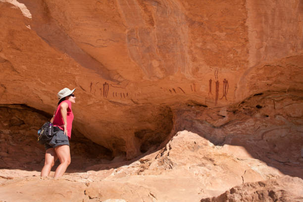 Woman inspects ancient Barrier Canyon style pictographs San Rafael Swell Utah stock photo