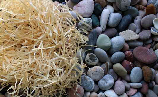 Straw bird’s nest on the sea stones on a shore top view hi-res photo