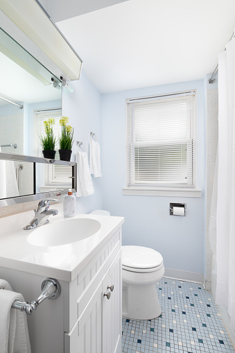 A blue bathroom with a white cabinet and blue square tile floor.