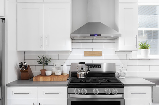 A kitchen detail shot with white cabinets, stainless steel appliances, granite countertops, and a subway tile backsplash.