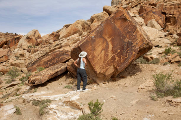 Woman inspects snake petroglyphs San Rafael Swell Utah stock photo